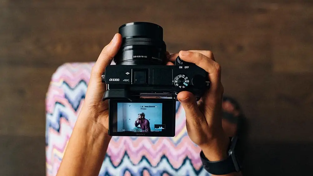 Vrouw maakt een portret van een man met een systeemcamera met een kantelbaar scherm 