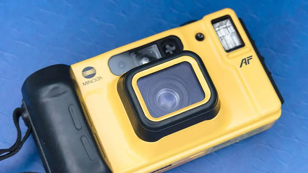 Een gele onderwatercamera van Minolta op een blauwe ondergrond.