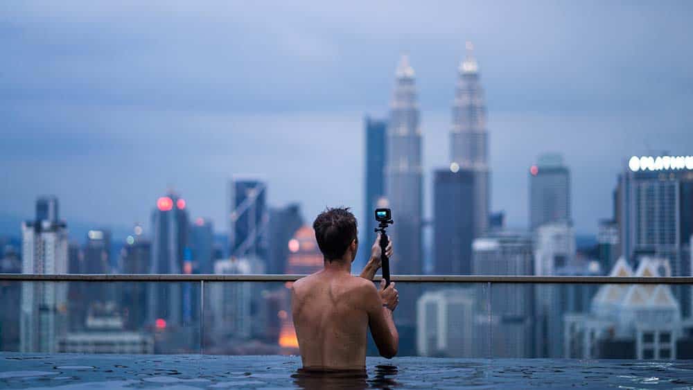 Man maakt foto van skyline vanuit zwembad met een action camera
