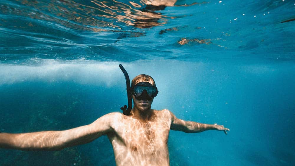 Man met duikbril en snorkel onder water