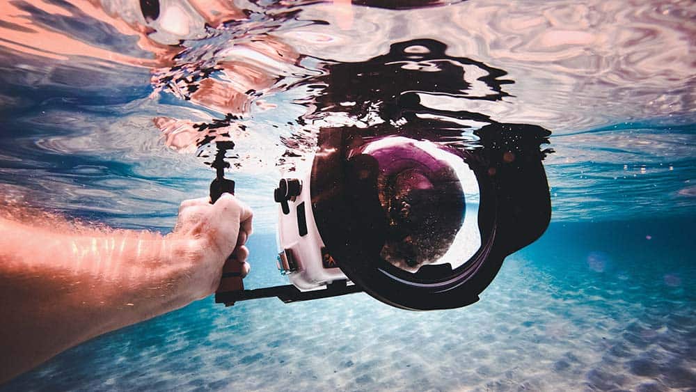 Man houdt spiegelreflexcamera onder water met waterdichte behuizing