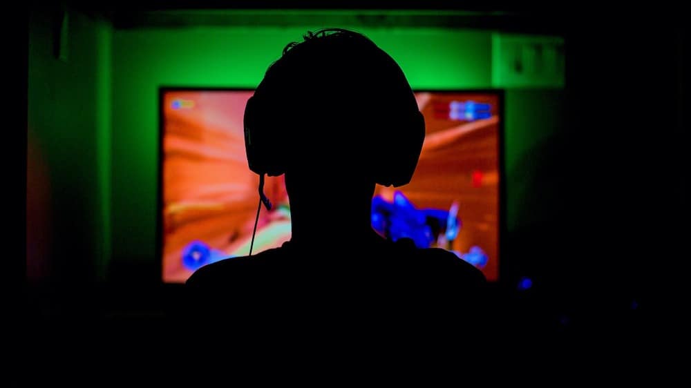 Een gamer van achteren gefotografeerd tijdens het gamen voor een scherm