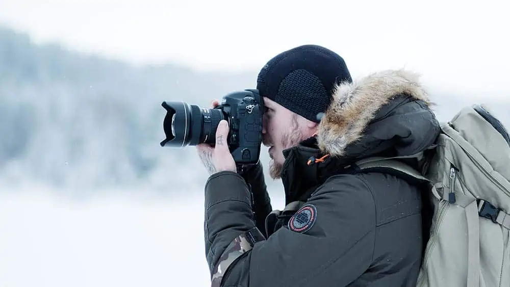 Man fotografeert in winterlandschap met een spiegelreflexcamera