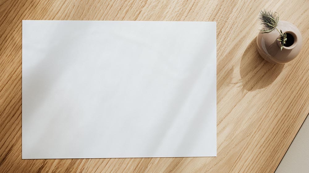 Een leeg vel printpapier op een houten tafel