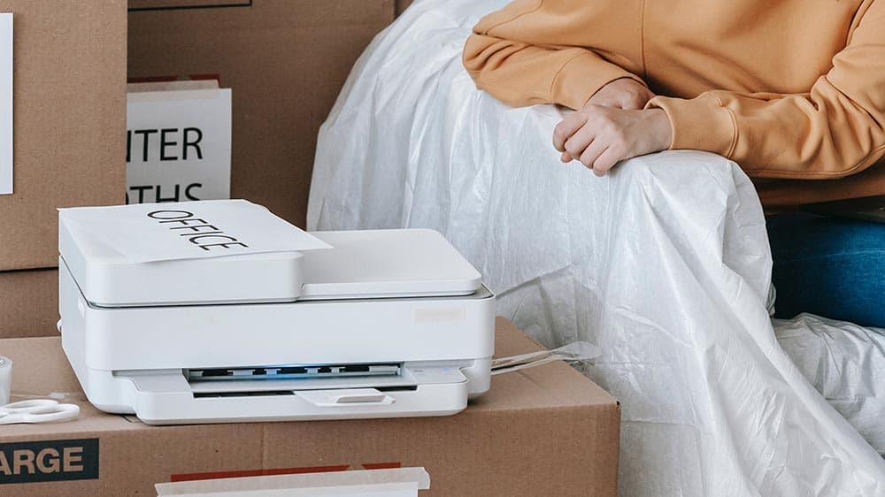 een witte all-in-one printer op een verhuisdoos