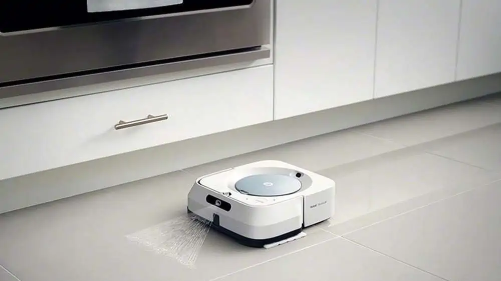 een witte dweilrobot maakt de vloer van een keuken schoon
