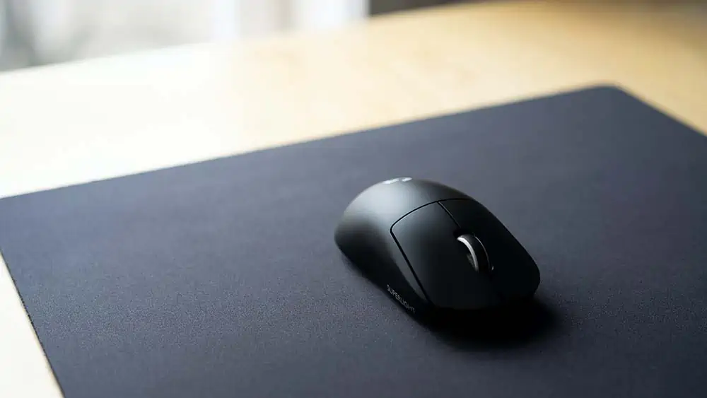 een zwarte draadloze muis op een muismat op een bureau