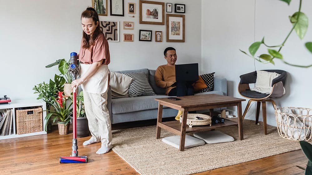 Vrouw maakt vloer van de woonkamer schoon met een draadloze stofzuiger