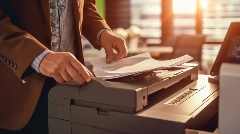 Man bladert door documenten op een grijze printer